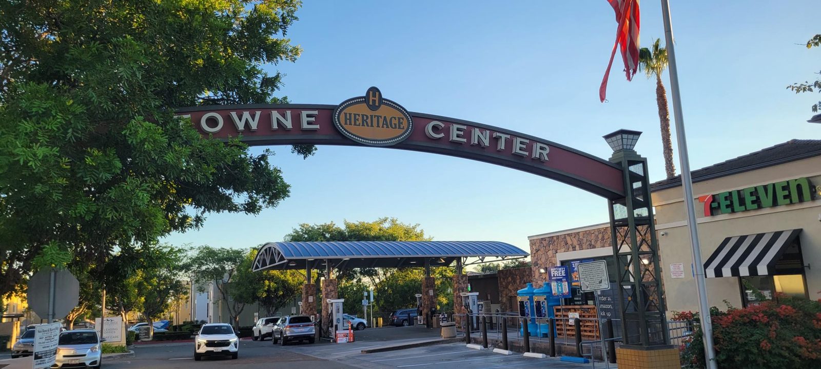 The arched Heritage Towne Center sign with its round Heritage medallion spanning the entrance to the shops, including a 7-Eleven, in Otay Ranch, Chula Vista