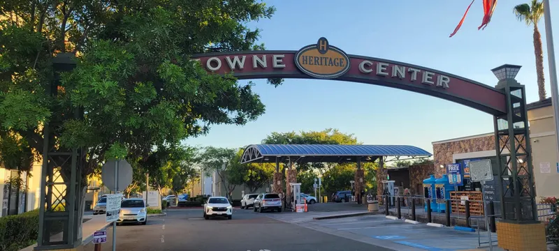 Wide view under the Heritage Towne Center arch toward the shaded parking lot and shops in Otay Ranch